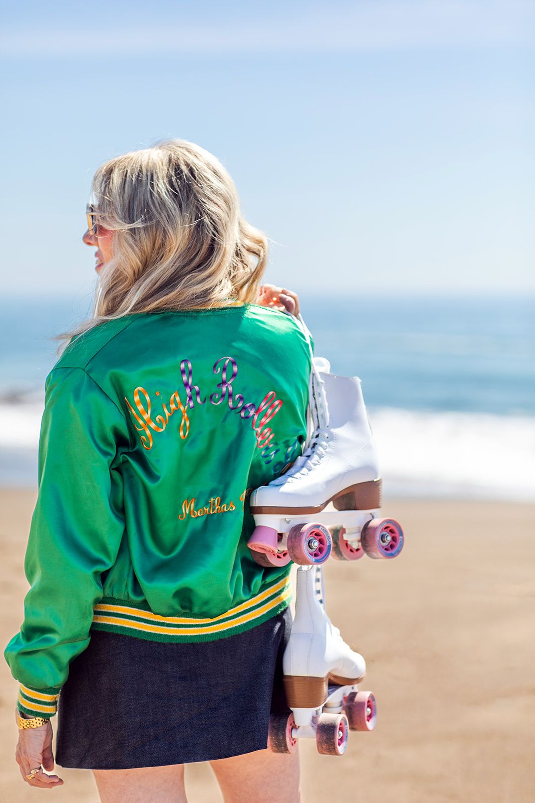 High Rollers artwork showing a woman in an embroidered High Rollers jacket carrying roller skates